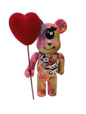 un ours en peluche tenant un ballon en forme de cœur au bout d'un bâton