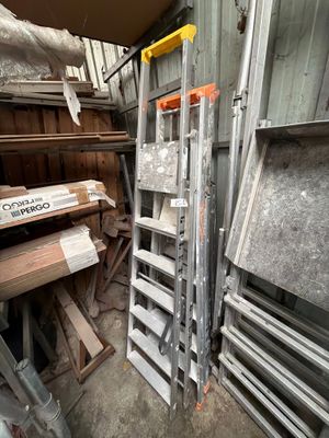 a pile of wood in a room with a ladder