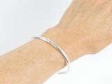 someone is holding a silver bracelet that has a curved design on it