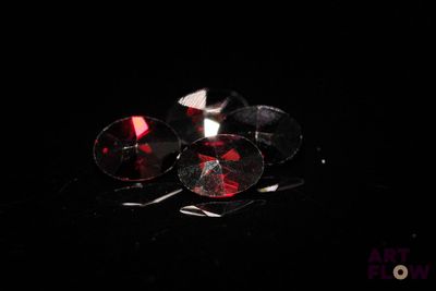 deux paires de boucles d'oreilles en cristal rouge et blanc posées sur un fond noir