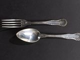 two spoons and a fork on a black table