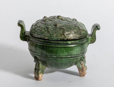 un petit pot vert muni d'un couvercle, posé sur un socle
