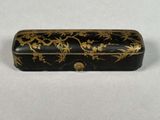 a black and gold box with flowers and leaves on it