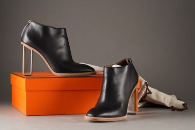 two pairs of black leather ankle boots sitting on top of an orange box