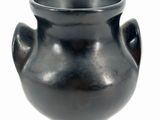 a black vase that is sitting on a white surface