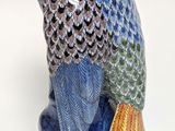a figurine of a blue and green owl sitting on a branch