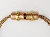 gold plated bracelet with two metal beads on a white surface