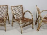 trois chaises en osier placées les unes à côté des autres sur un sol blanc