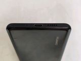 the back of a black cell phone sitting on top of a white table