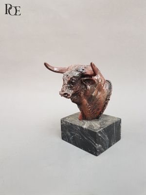 sculpture représentant une tête de taureau posée sur un socle en marbre, sur fond blanc