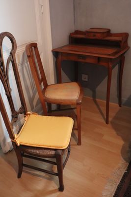 two wooden chairs and a desk in a small room