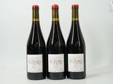 trois bouteilles de vin rouge sont posées sur une surface blanche
