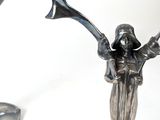 two silver candlesticks with a woman holding a top hat