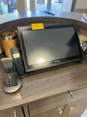 a desk with a laptop, phone, and other items on it