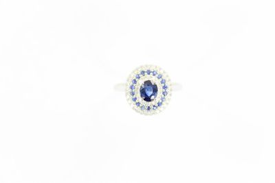 un gros plan d'une bague ornée d'une pierre bleue entourée de diamants bleus et blancs