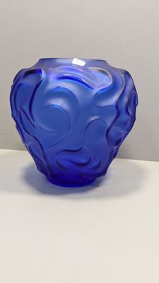 un vase en verre bleu posé sur une table blanche