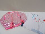 une chemise blanche et une veste rose posées sur une table blanche