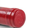 a close up of a red wine bottle on a white surface