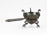 une petite casserole en métal munie d'une poignée et d'une cuillère posée dessus