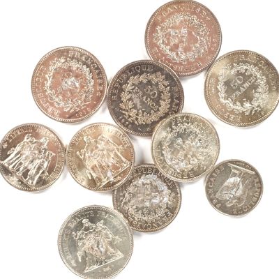 Plusieurs pièces de monnaie britanniques sont disposées en cercle sur une surface blanche.