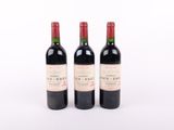 trois bouteilles de vin rouge posées l'une à côté de l'autre sur une surface blanche