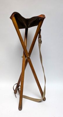 a small wooden stool with a leather seat on a white background