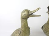 two bronze ducks that are standing next to each other