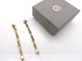 deux paires de boucles d'oreilles dans un écrin posé sur une surface blanche