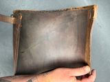 someone is holding a brown leather bag with a tattoo on it