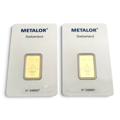 Deux lingots d'or sont posés côte à côte sur une surface blanche.