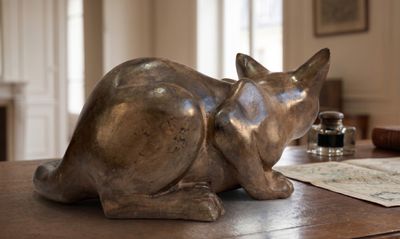 une statue représentant un chat assis sur une table en bois