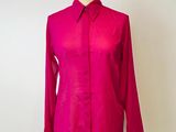 La chemise rose est posée sur un présentoir à mannequin, devant un fond blanc.