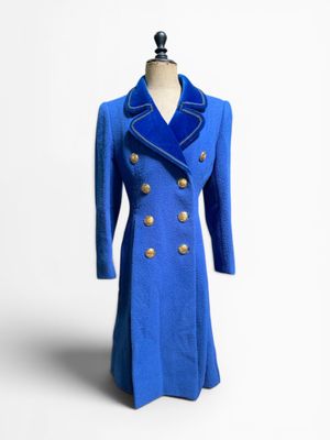 manteau en laine bleue avec des boutons dorés, posé sur un socle de mannequin