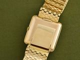 an image of a gold watch sitting on top of a green surface
