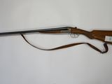 the rifle is laying on a white surface with a brown strap