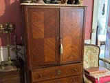 a cabinet and chair in a room with a painting on the wall