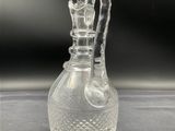 a clear glass vase with a handle on a table