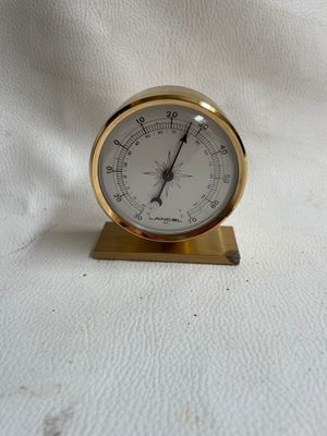 une petite horloge dorée posée sur une surface blanche