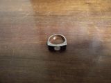 une bague en argent posée sur une table en bois, sur laquelle se trouve une bague noire