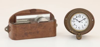 a small clock sitting next to a box with a mirror