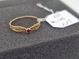 a close up of a gold ring with a red stone on it