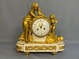 a gold clock sitting on top of a marble base
