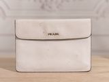 a white purse sitting on top of a wooden table next to a wall