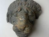 une statue représentant une tête de lion sur un fond blanc