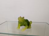 une figurine de grenouille verte posée sur une table en verre