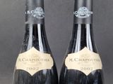 pair of bottles of wine sitting on top of a wooden table