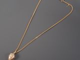 a gold plated necklace with a pearl pendant on a chain