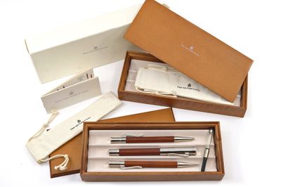 Plusieurs stylos et crayons se trouvent dans une boîte posée sur une surface blanche.