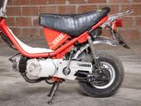a small red motorcycle parked in front of a brick wall