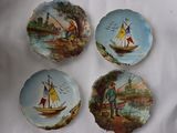 quatre assiettes décoratives ornées de bateaux peints, posées sur une table